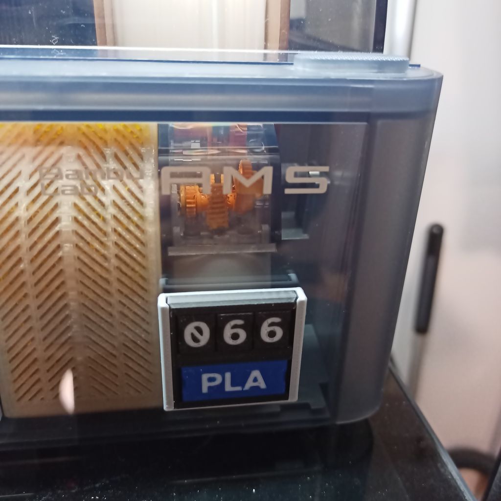 A Case attached to the front of a Bambu Lab AMS. The tag reads "066 PLA".